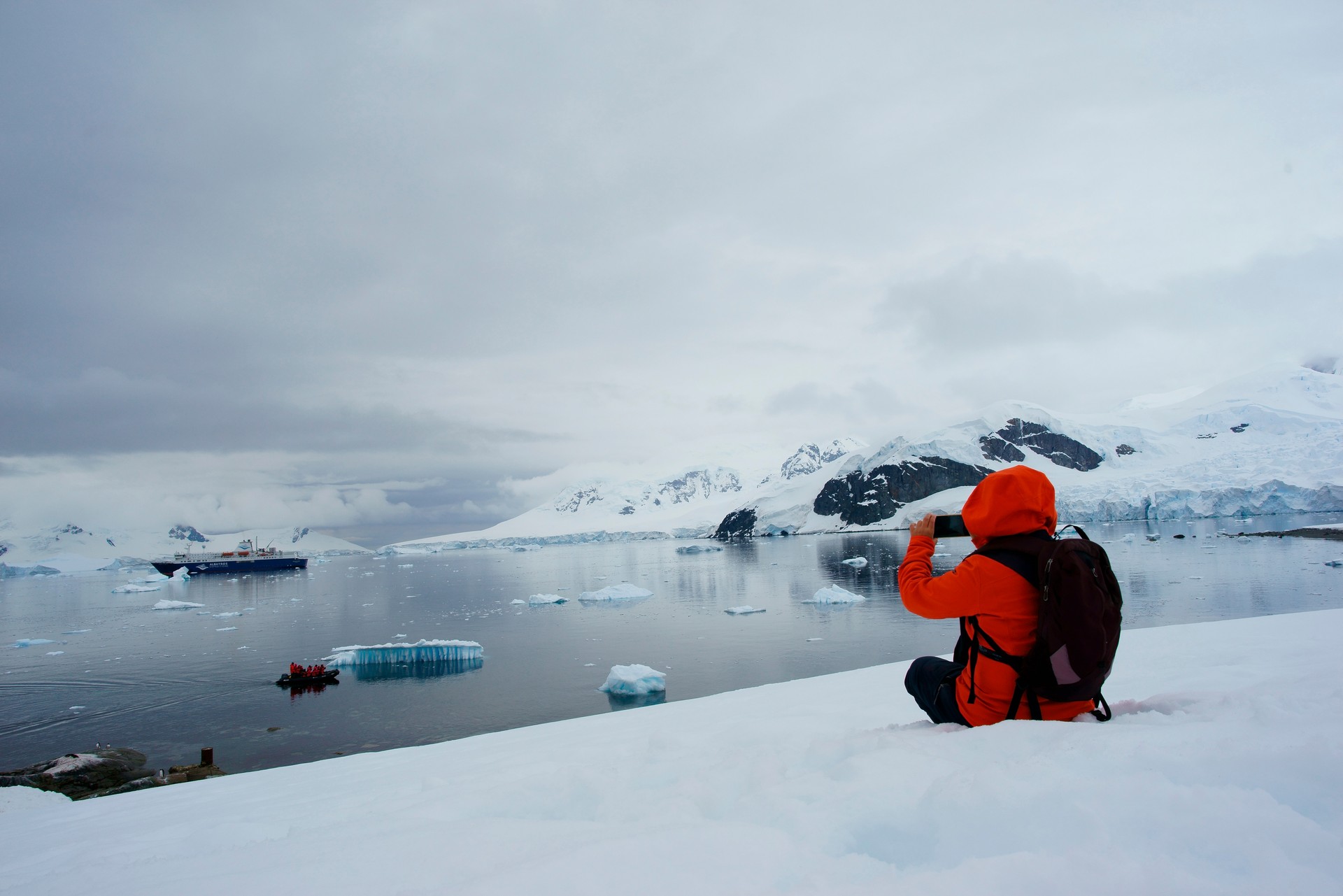 Woman hikes takes photo Antarctic Peninsula mountain Orne Harbour Gerlache Strait Antarctica